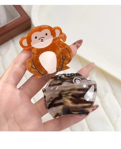 Close-up of cute acetate hair claws in monkey and wild boar shapes held by hand