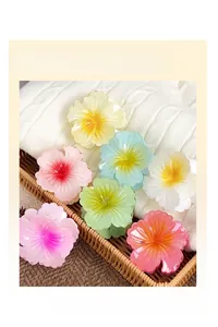 Macro shot of 7 colorful translucent resin flower hair claws on white knit texture