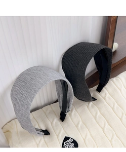 Detail of grey and charcoal knitted wide headbands with ribbed texture on fabric surface