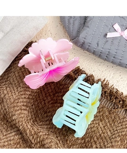 Detailed view of large flower hair claws in pink and blue on a textured fabric background