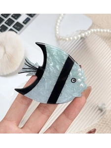 Détail de la pince à cheveux poisson bleu avec perles et texture effet marbre