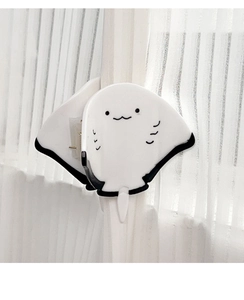 Macro shot of cute white acetate stingray hair claw clip on white curtain background