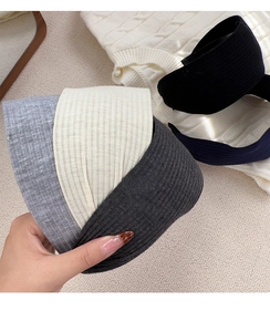 Detailed close-up of wide ribbed knit headbands in grey, beige, and black colors