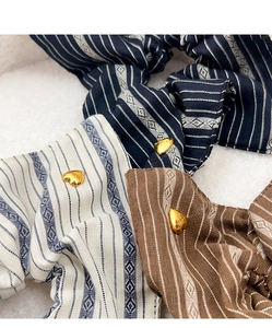 Detail of three striped fabric scrunchies with heart-shaped metal charms on faux fur