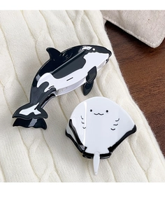 Detailed view of glossy acetate orca and stingray hair claws on knit sweater