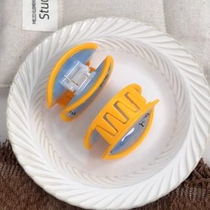 Ghost themed blue acetate hair claw clips with orange contrast on a ceramic display
