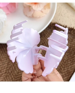 Detail of a matte lavender flower hair claw clip with a silver spring on a soft floral backdrop