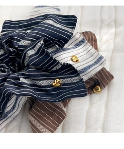 Close-up of striped fabric scrunchies featuring heart-shaped gold charms on knit surface