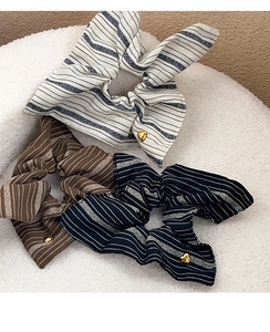 Detail of striped fabric hair scrunchies with golden heart charms in neutral tones