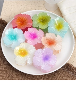 Flat lay of colorful flower hair claws in a white tray with various summer-inspired hues