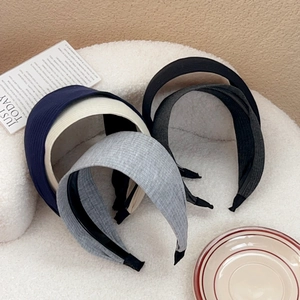 Set of wide ribbed knit headbands in navy, grey, black and beige on soft background