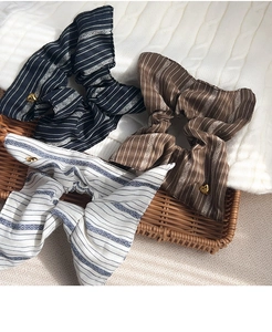 Detail of vintage striped fabric scrunchies with heart charm on a bamboo tray
