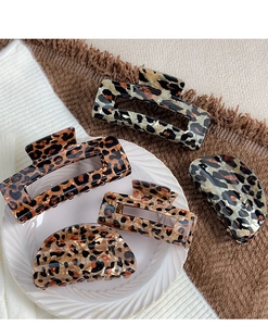 Detailed flat lay of leopard print hair claw clips in various shapes on a textured tray