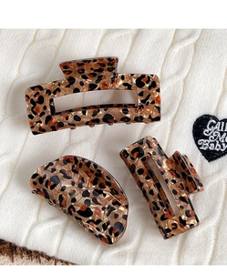 Three pieces of leopard print claw clips in various shapes on a textured sweater