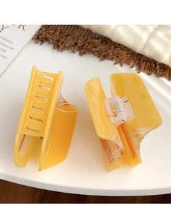 Detail of two large amber claw clips featuring premium acetate texture and metal springs