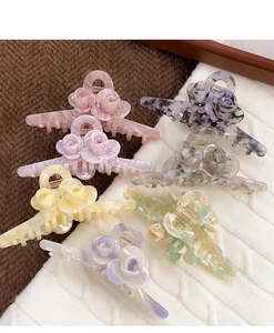 Detailed view of large marble-textured acetate hair claws with dual rose flower accents