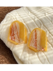 Detail of orange resin hair claws with white abstract lines on a knit sweater background