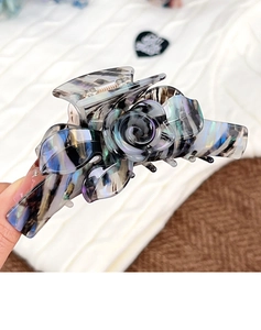 Gros plan d'une pince à cheveux fleur en acétate haut de gamme avec texture marbrée