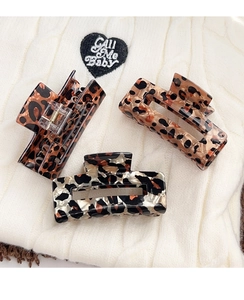 Detail of vintage leopard print hair clips on a white knitted sweater background