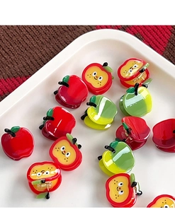 Detail view of cute red apple acetate hair claws and clips in a white display tray
