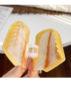 Detail view of large amber resin hair claw with orange marble pattern and metal spring