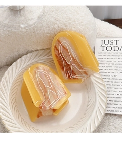 Detail view of amber resin hair claws with minimalist line art on white relief plate