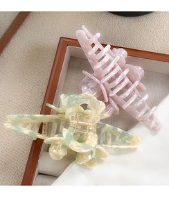 Macro shot of large marble pattern hair claws with rose motifs in a wooden display tray