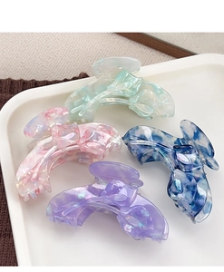 Detail of four acetate tulip flower hair claws with marble texture in a white tray