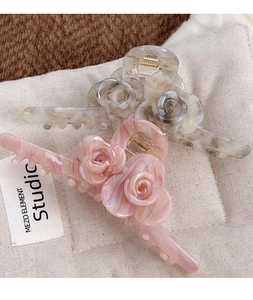 Detail of rose-shaped claw clips in pink and cream with elegant marble texture