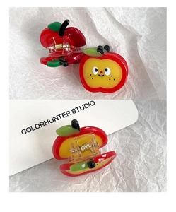Close-up of cute red apple hair claw clip for kids with cartoon face and metal spring