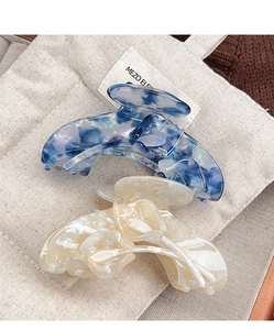 Detail view of large tulip hair claws in marble purple and pearl white acetate material