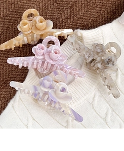 Close-up of elegant rose hair claws in pearl texture colors on a knitted background