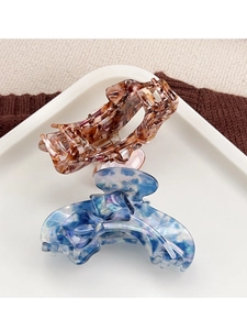 Detail of brown tortoiseshell and blue marble acetate hair claws on ceramic plate