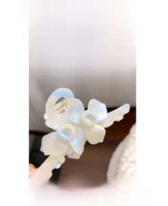 Détail de la pince à cheveux en acétate blanc avec design floral nacré et ressort doré
