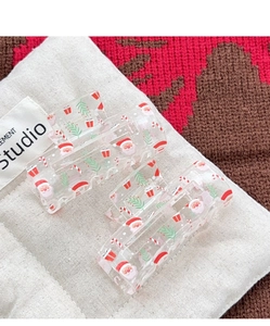 Detail of transparent Christmas hair claws with Santa prints on white cotton cushion