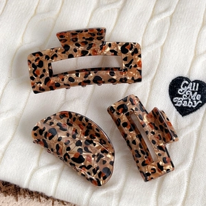 Three-piece set of leopard print hair claw clips in amber and black on a knit background