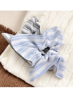 Détail du chouchou à nœud rayé bleu et blanc sur un pull en tricot beige doux