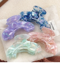 Detail of four colorful acetate tulip hair claws with elegant marble texture and pearl luster