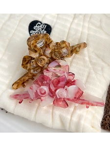 Détails de pinces à cheveux fleurs en écaille et marbre rose sur un tricot blanc moelleux
