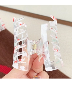 Close-up of transparent Christmas claw clip with festive candy cane print and metal spring