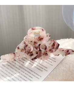 Gros plan sur une pince à cheveux fleur en acétate avec texture marbrée rose élégante