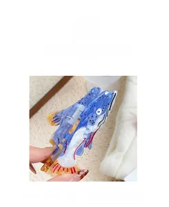 Detail of whale-shaped hair claw clip with blue and white marble pattern and red fin
