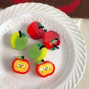 Cute apple-shaped acetate hair claws for kids with glossy finish on a white plate