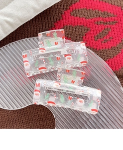 Close-up of clear acrylic Christmas hair claws with festive Santa and tree patterns