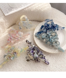 Vue détaillée de pinces à cheveux fleur en acétate avec textures marbrées et ressort doré robuste