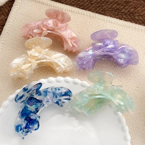 Elegant tulip-shaped acetate hair claws in five colors on a decorative ceramic plate