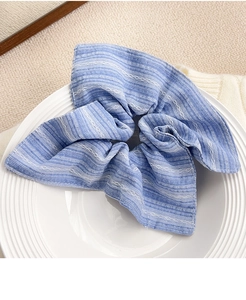Détail d'un chouchou à rayures bleues sur une assiette en céramique blanche épurée