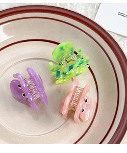 Detailed view of small octopus hair clips in purple, green, and pink acetate material