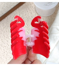 Detail view of large heart-shaped hair claw clip with pink and red color contrast and spring