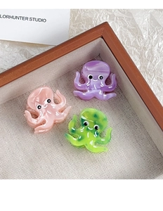 Detailed macro view of colorful octopus-shaped acetate hair clips in a wooden tray